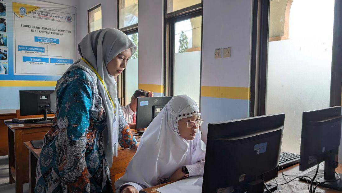 A lecturer sitting with a student at her computer